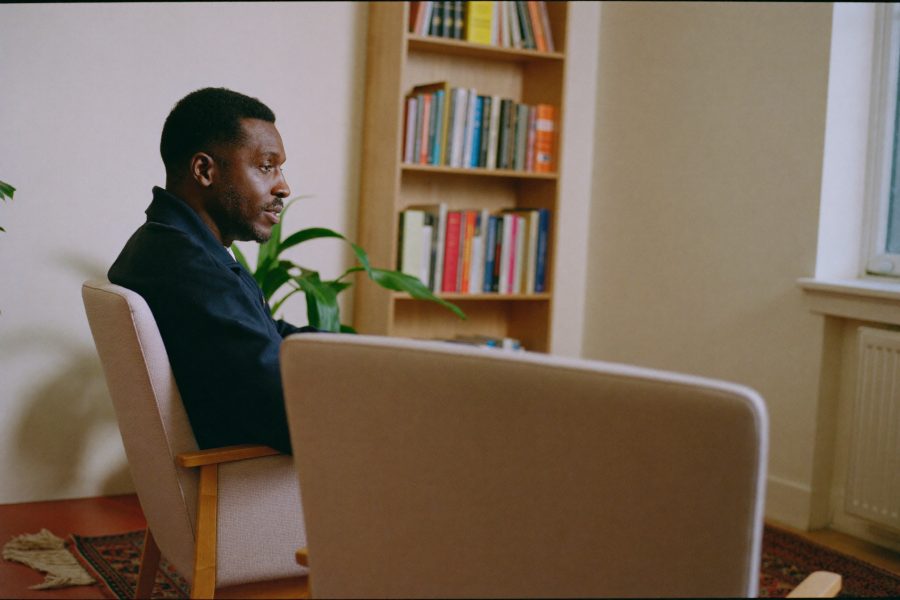 A calm consulting room with two armchairs set at an angle, a bookshelf and soft window light