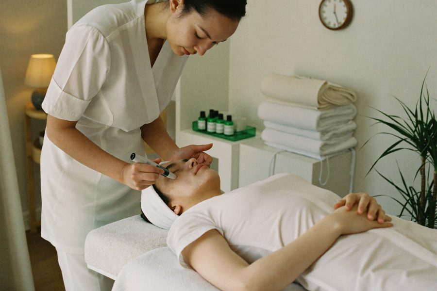 A beauty therapist preparing a treatment room with folded towels and warm lamp light