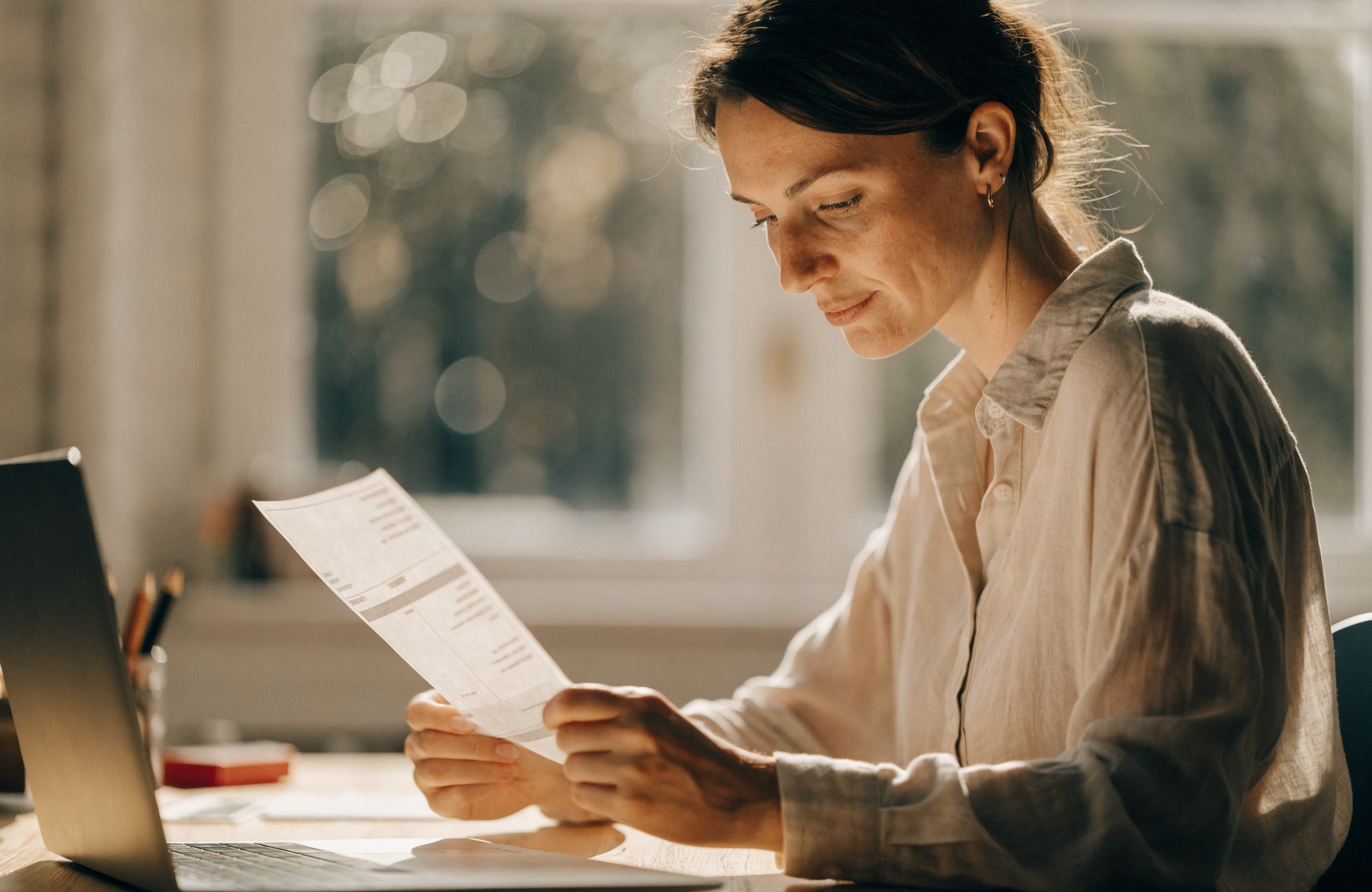 An independent professional reviewing an invoice at her desk